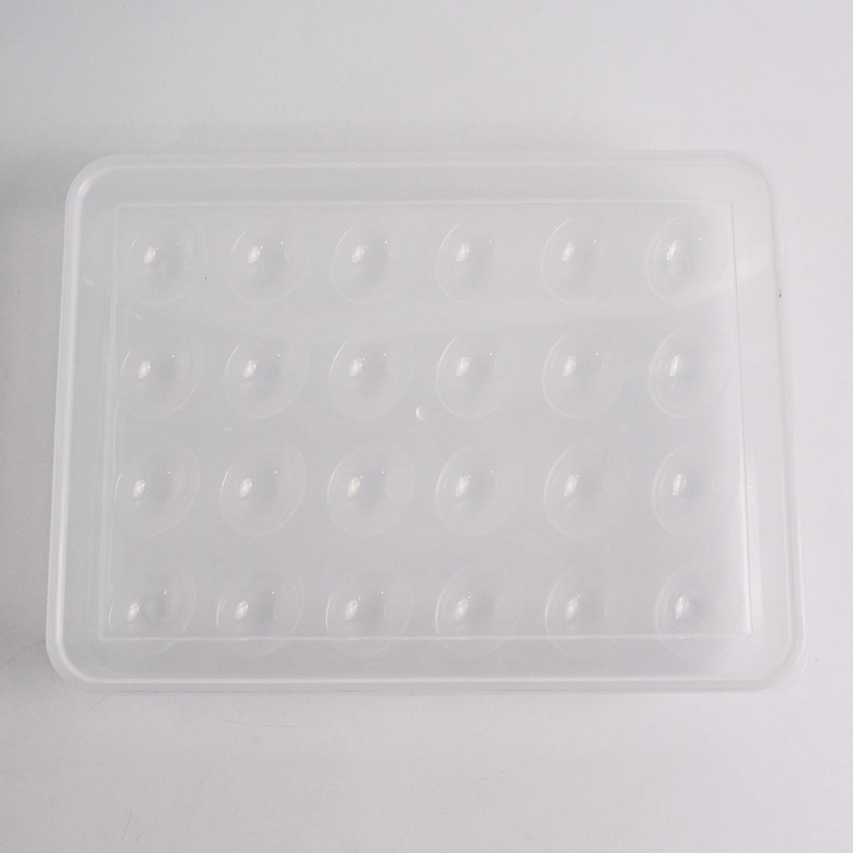 Clear plastic egg container next to traditional egg carton for size comparison