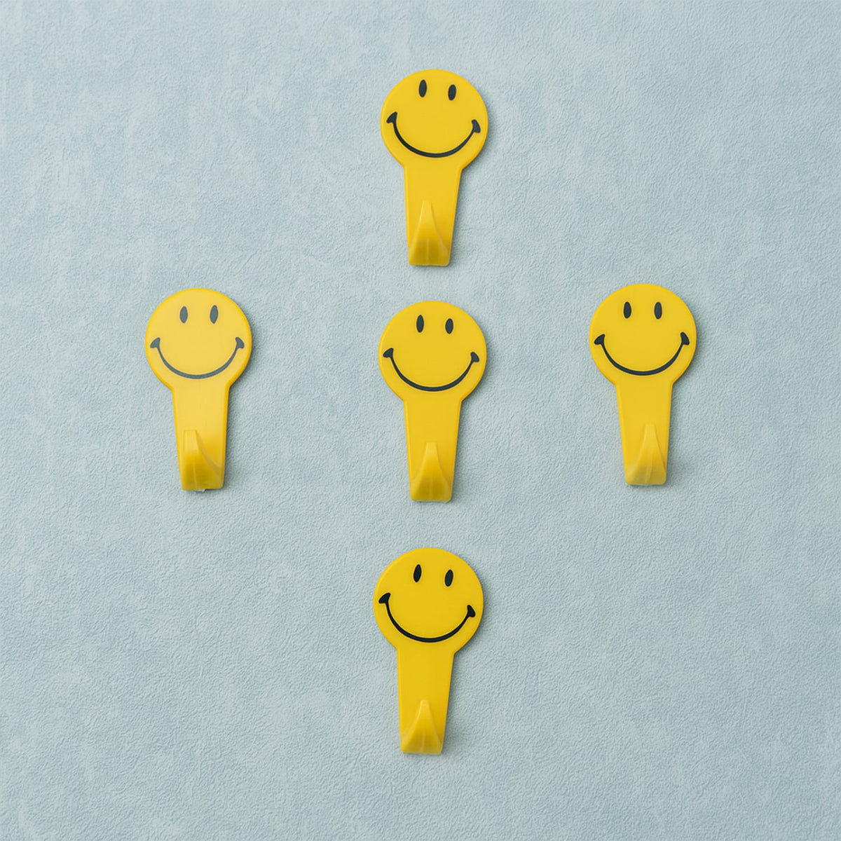 A set of five white self adhesive hooks displayed on a clean surface.